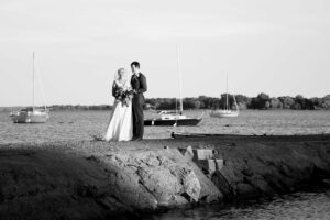 Black and white picture of a newlywed couple standing on a rock